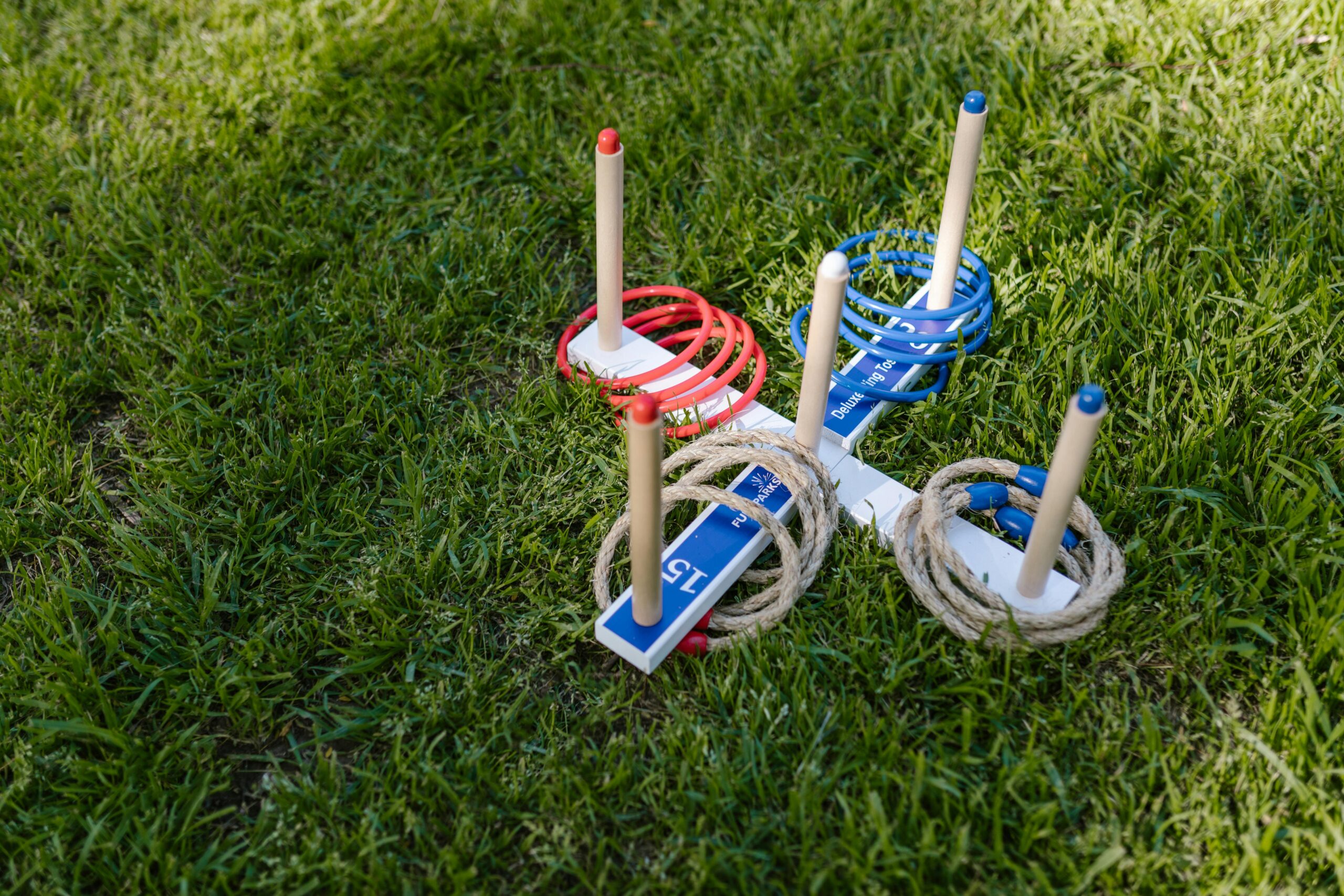 Ring toss game set on grass with red and blue rings around wooden pegs.