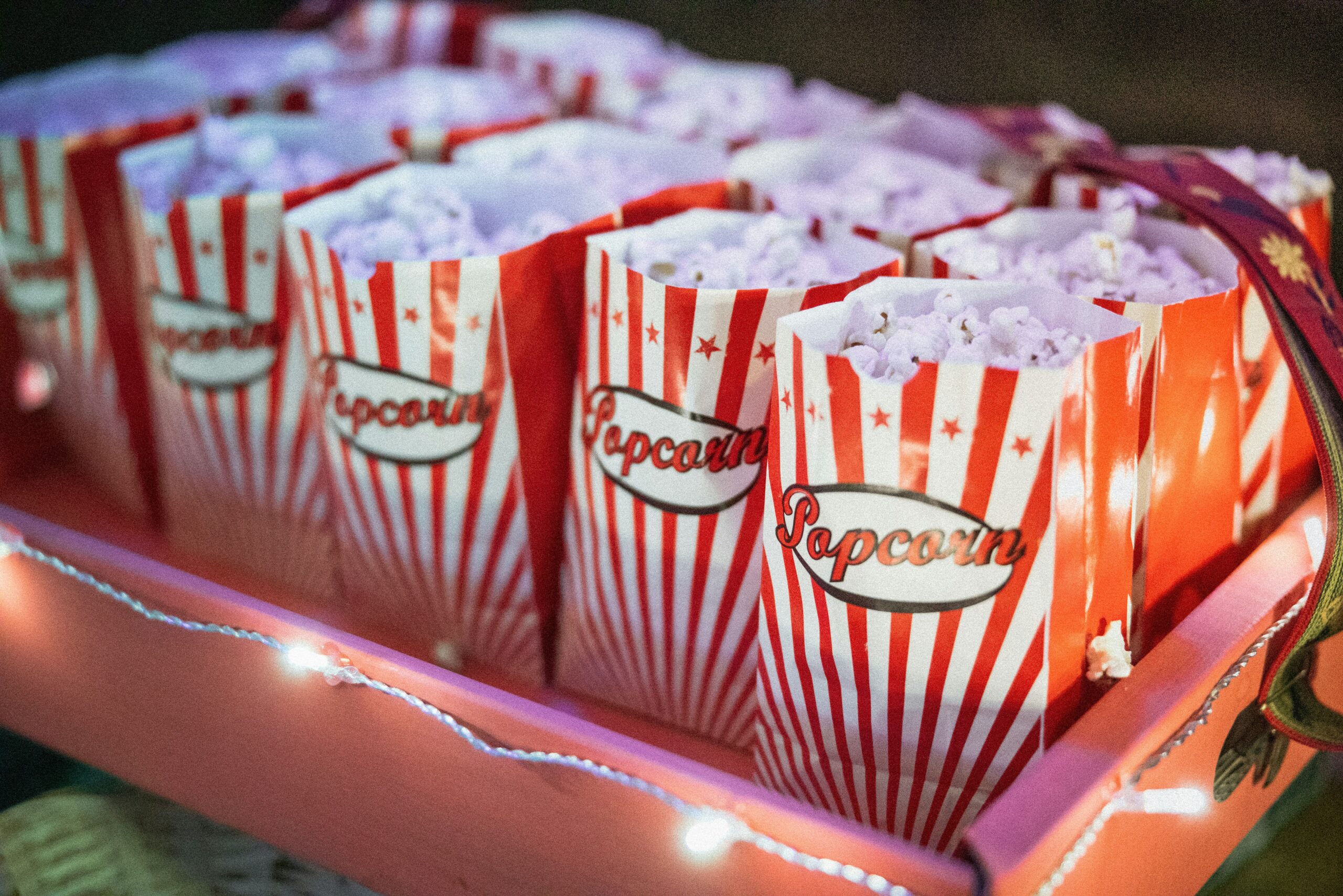 Striped popcorn boxes filled with popcorn arranged in a tray with lights.