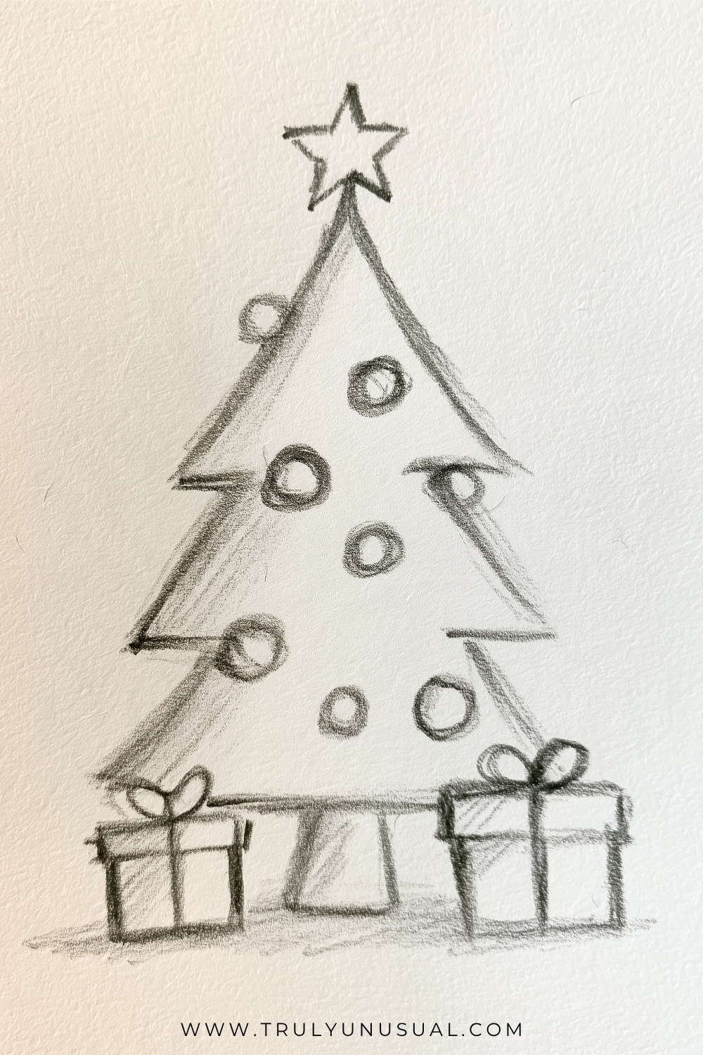 Easy Christmas tree pencil drawing featuring a simple evergreen tree made from three overlapping triangular layers, decorated with round Christmas baubles and topped with a five-pointed star. Two wrapped Christmas presents with ribbons and bows sit on either side of the tree trunk. Hand-drawn graphite pencil sketch with soft shading on textured cream paper, illustrating a cute Christmas drawing idea for beginners.