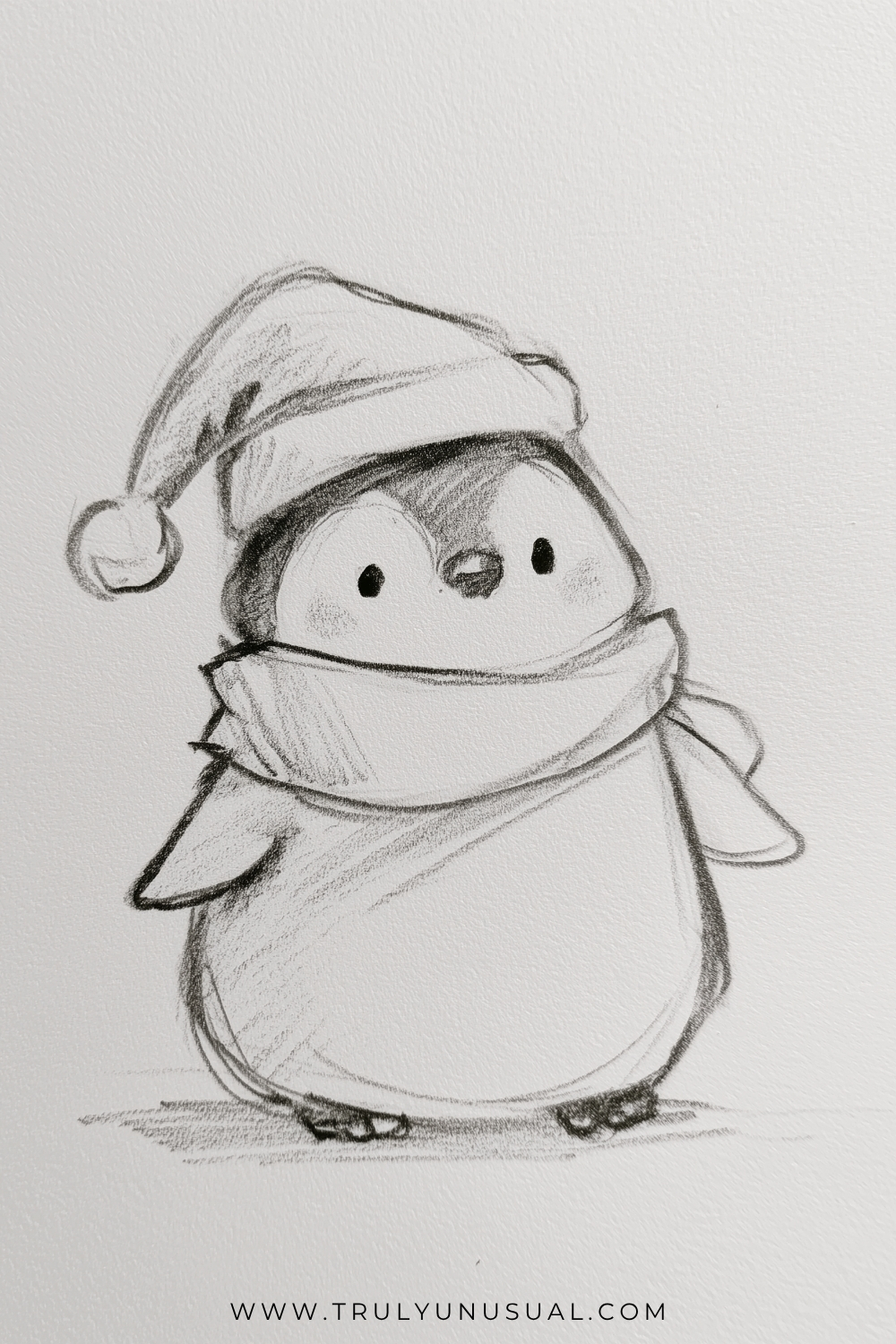 Cute Christmas penguin pencil drawing wearing a floppy Santa hat with a pom-pom and a cozy scarf wrapped around its neck. The penguin has a round body, tiny flippers, small feet, and an adorable face with rosy cheeks. Soft graphite shading adds depth to this easy Christmas drawing idea.