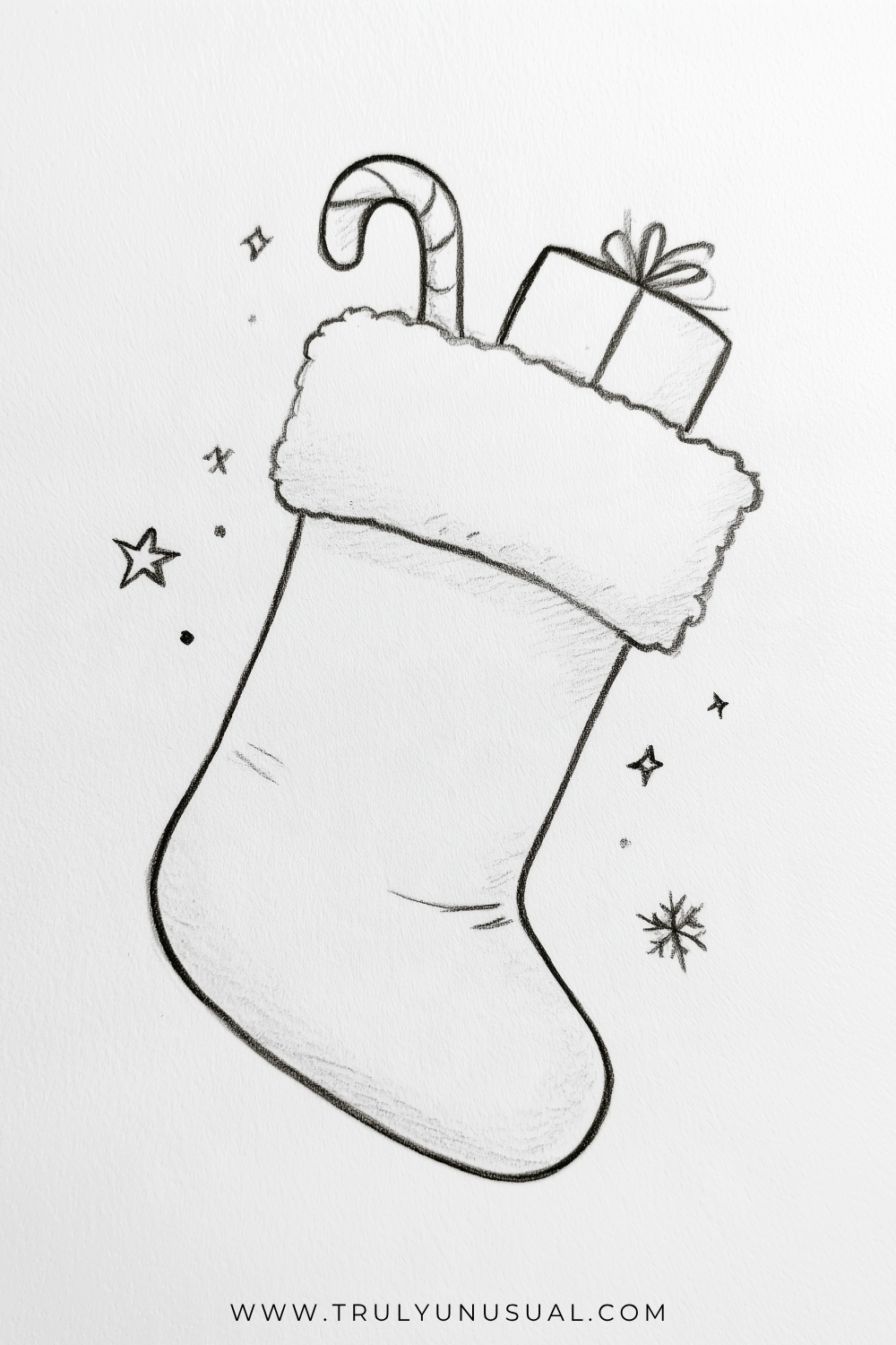 Easy Christmas stocking pencil drawing featuring a fluffy stocking filled with a striped candy cane and a small wrapped Christmas present with a bow, surrounded by hand-drawn stars and festive sparkles.
