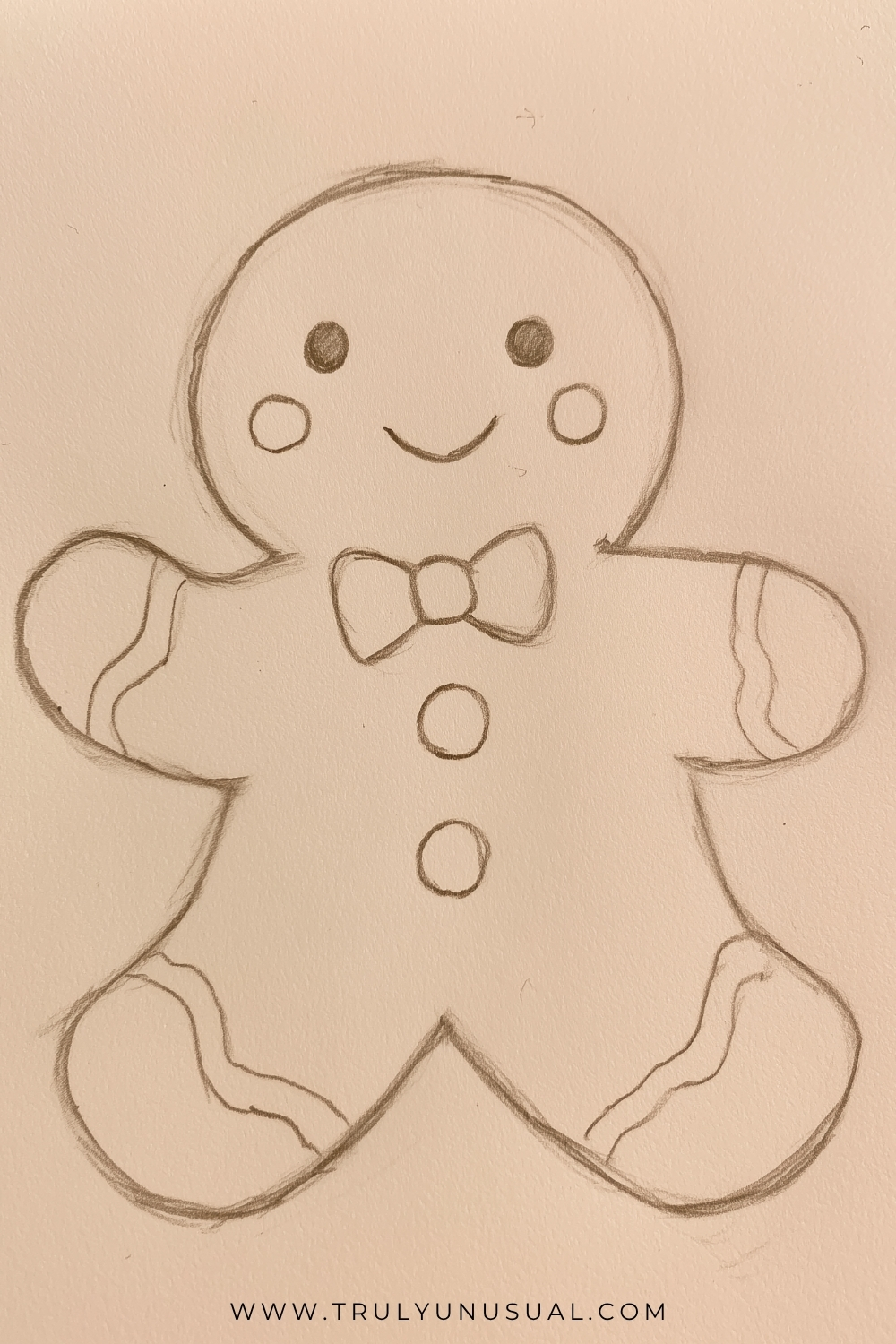 Cute and easy gingerbread man pencil drawing featuring a smiling Christmas gingerbread cookie with a large round head, two dark circular eyes, round cheeks, and a happy curved mouth. The gingerbread man has outstretched arms, rounded legs, a decorative bow tie, two circular buttons, and wavy icing patterns on its hands and feet. Simple hand-drawn pencil sketch on a warm beige paper background, perfect for beginner Christmas drawing inspiration.