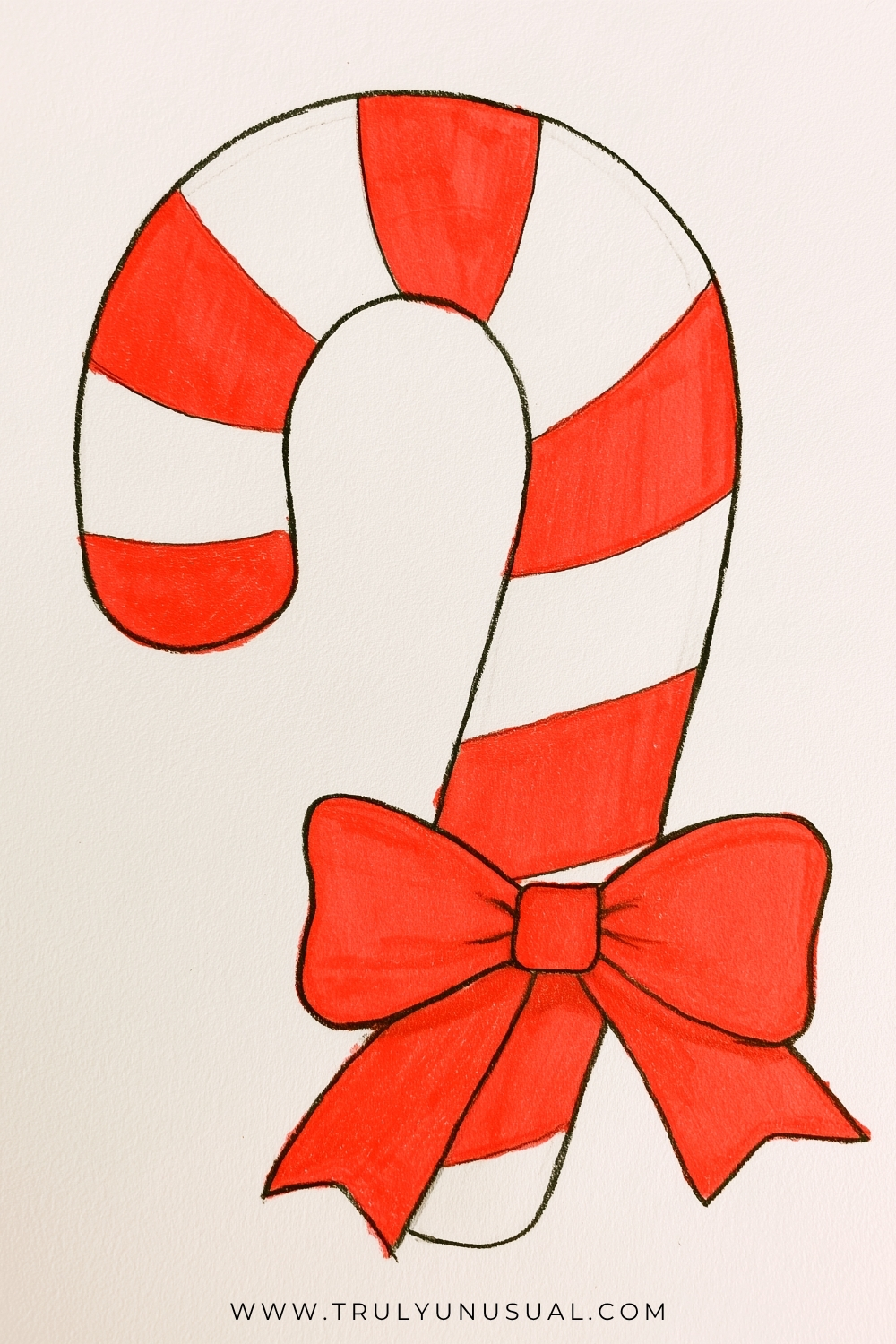Cute Christmas candy cane drawing featuring a large, curved candy cane decorated with alternating bright red and white stripes. An oversized red ribbon bow is tied around the lower section, with two rounded loops, a square center knot, and long flowing ribbon tails with pointed ends. The illustration has simple black pencil outlines and neatly colored red sections on a lightly textured white paper background, creating a cheerful and easy Christmas drawing idea for kids and beginners.